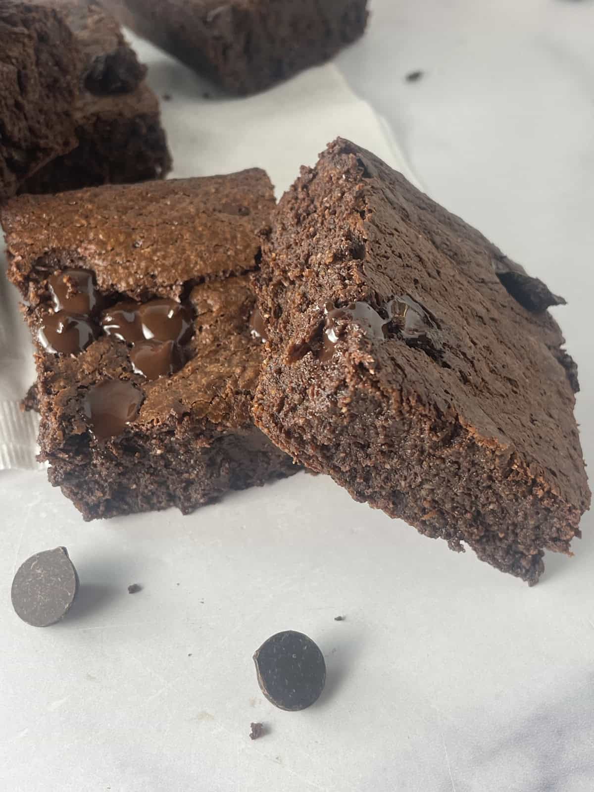 Fudgy chocolatey brownies on a counter with chocolate chips.