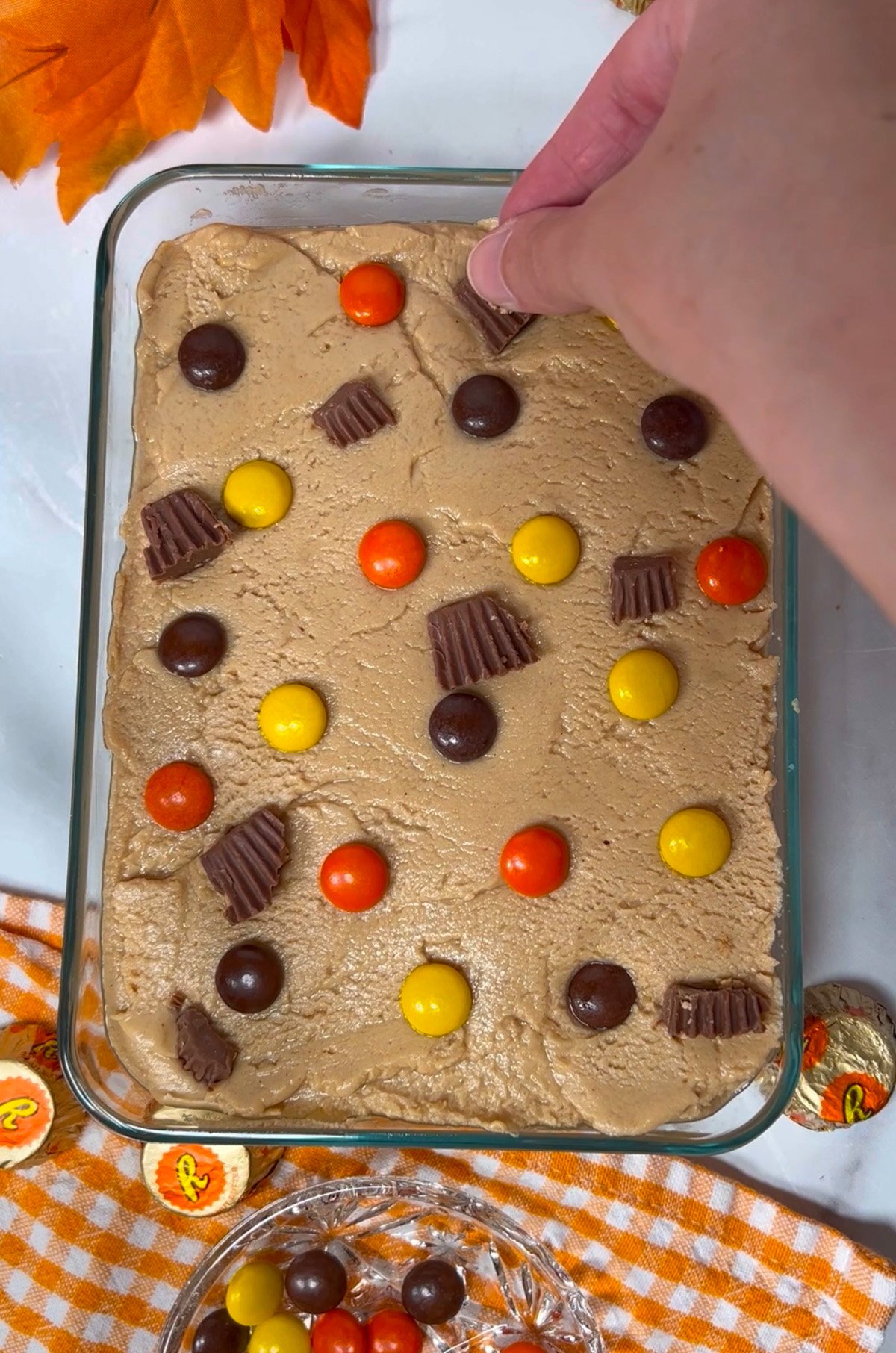 Placing Reese's pieces on top of fudge.