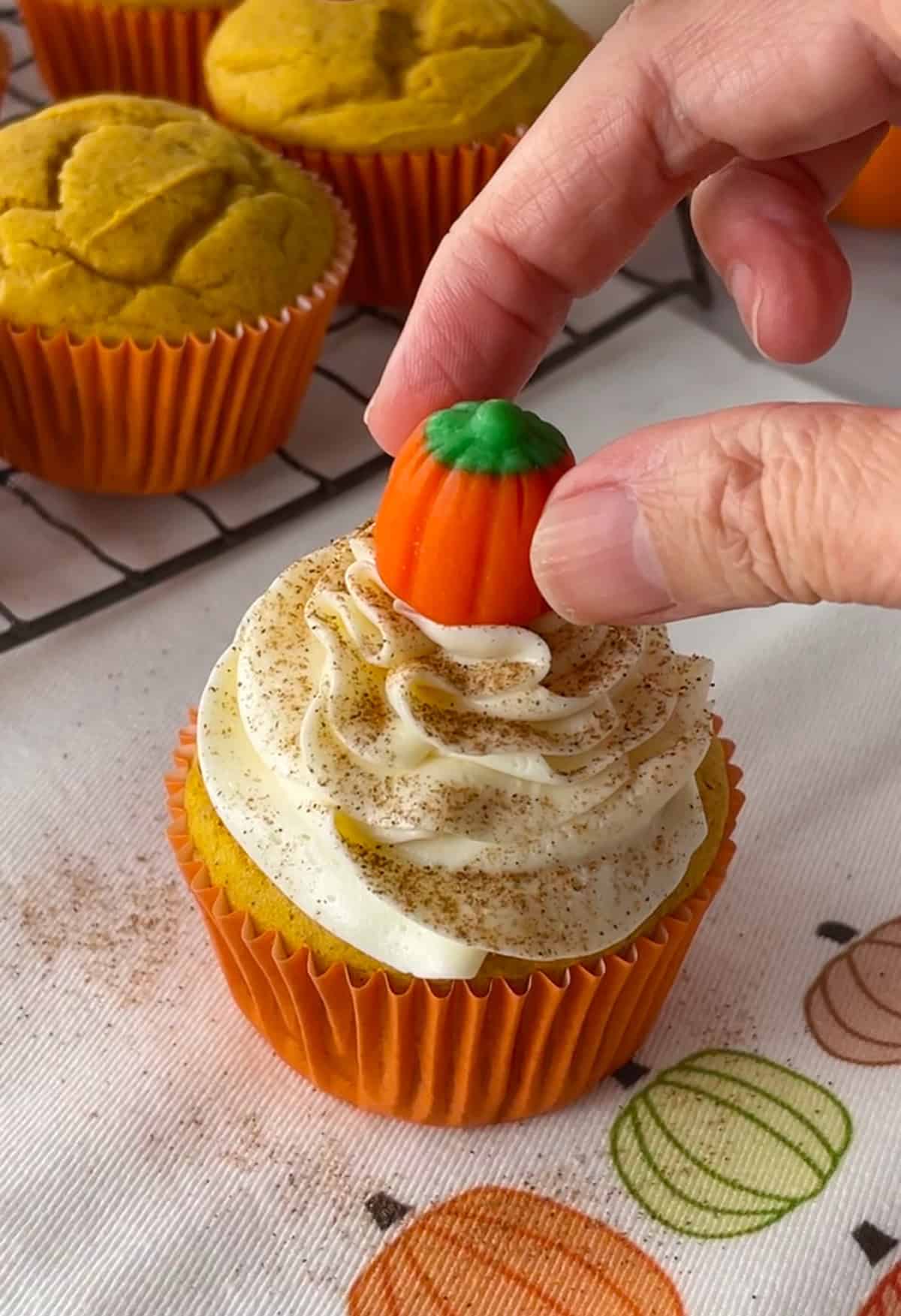 Placing candy corn pumpkin on top of cupcake.