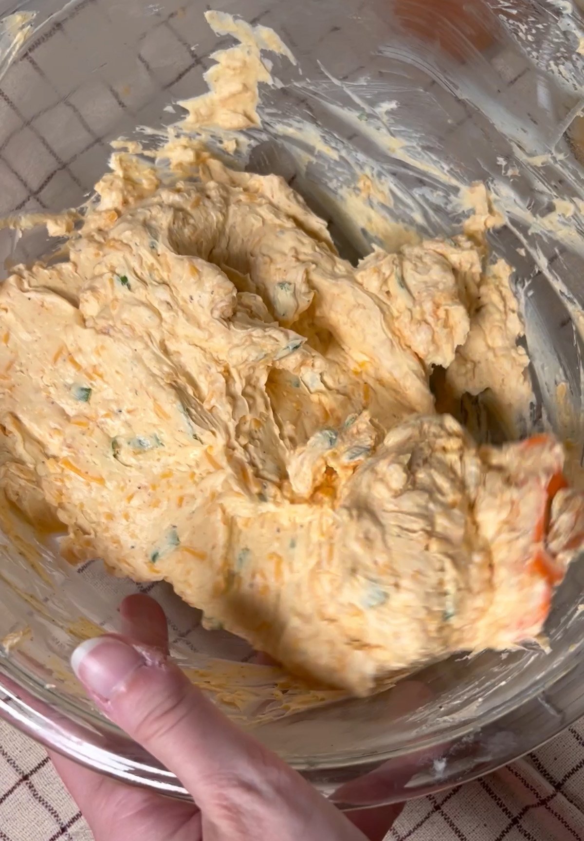 Mixing cheese ball ingredients in a glass bowl.