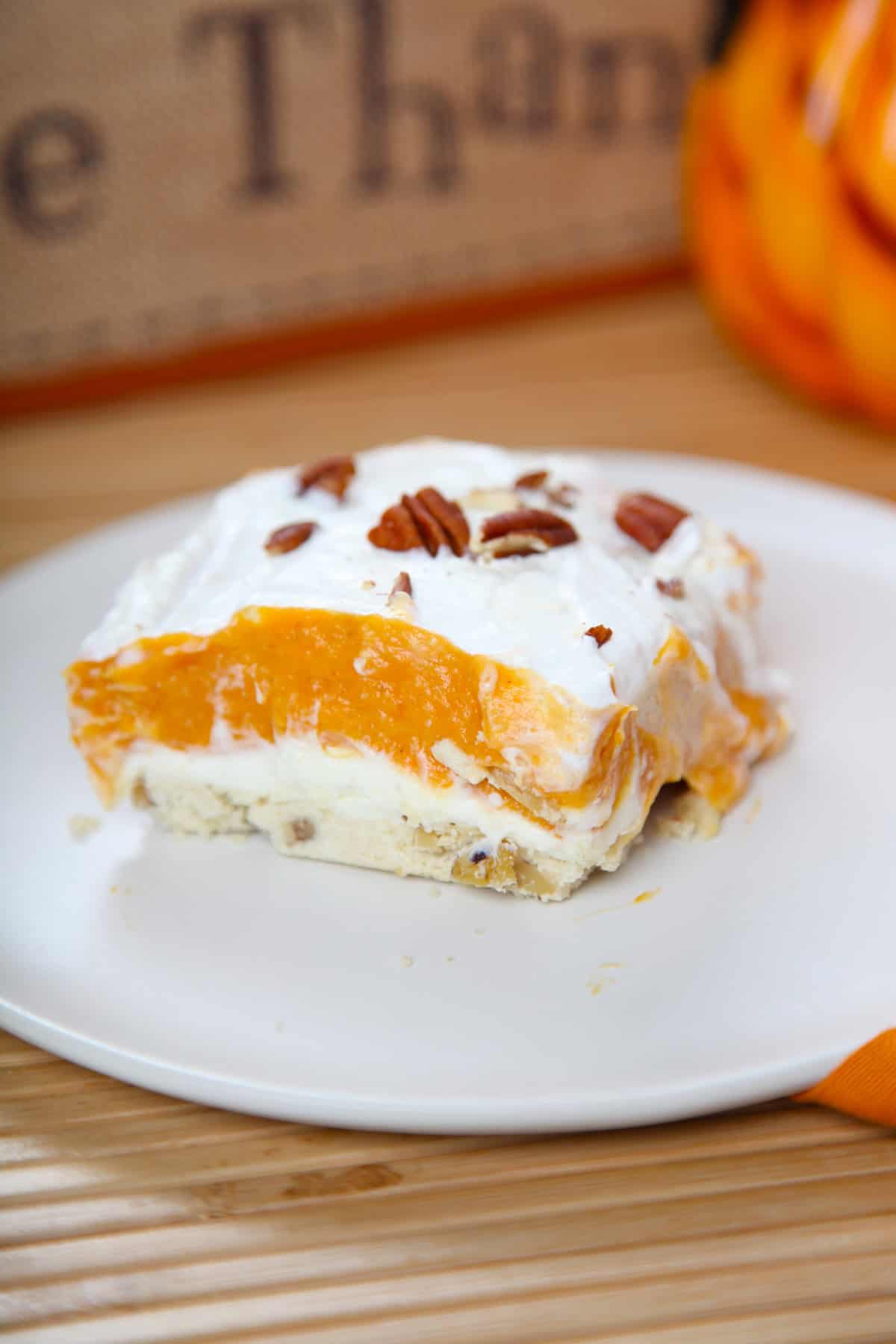 No bake pumpkin lasagna dessert cut into a square serving on a plate.