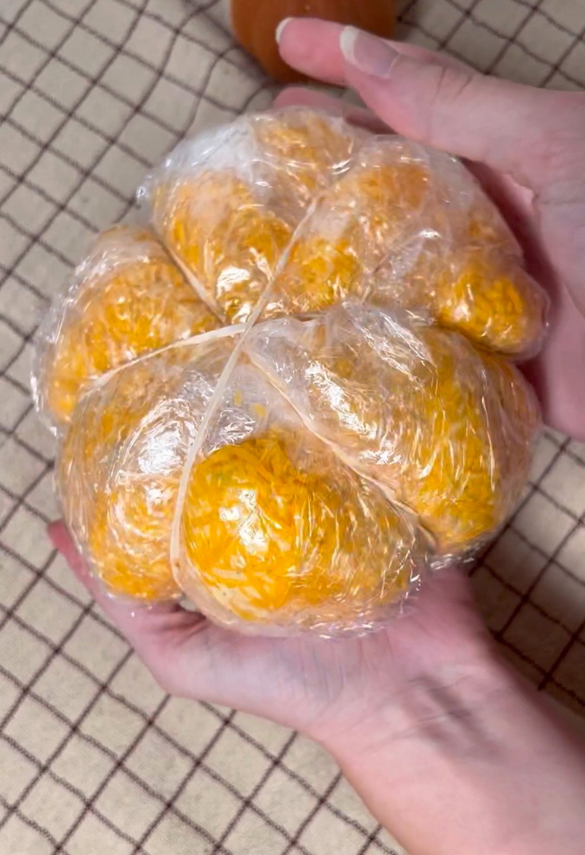 Shaping a pumpkin cheese ball with plastic wrap and rubber bands.