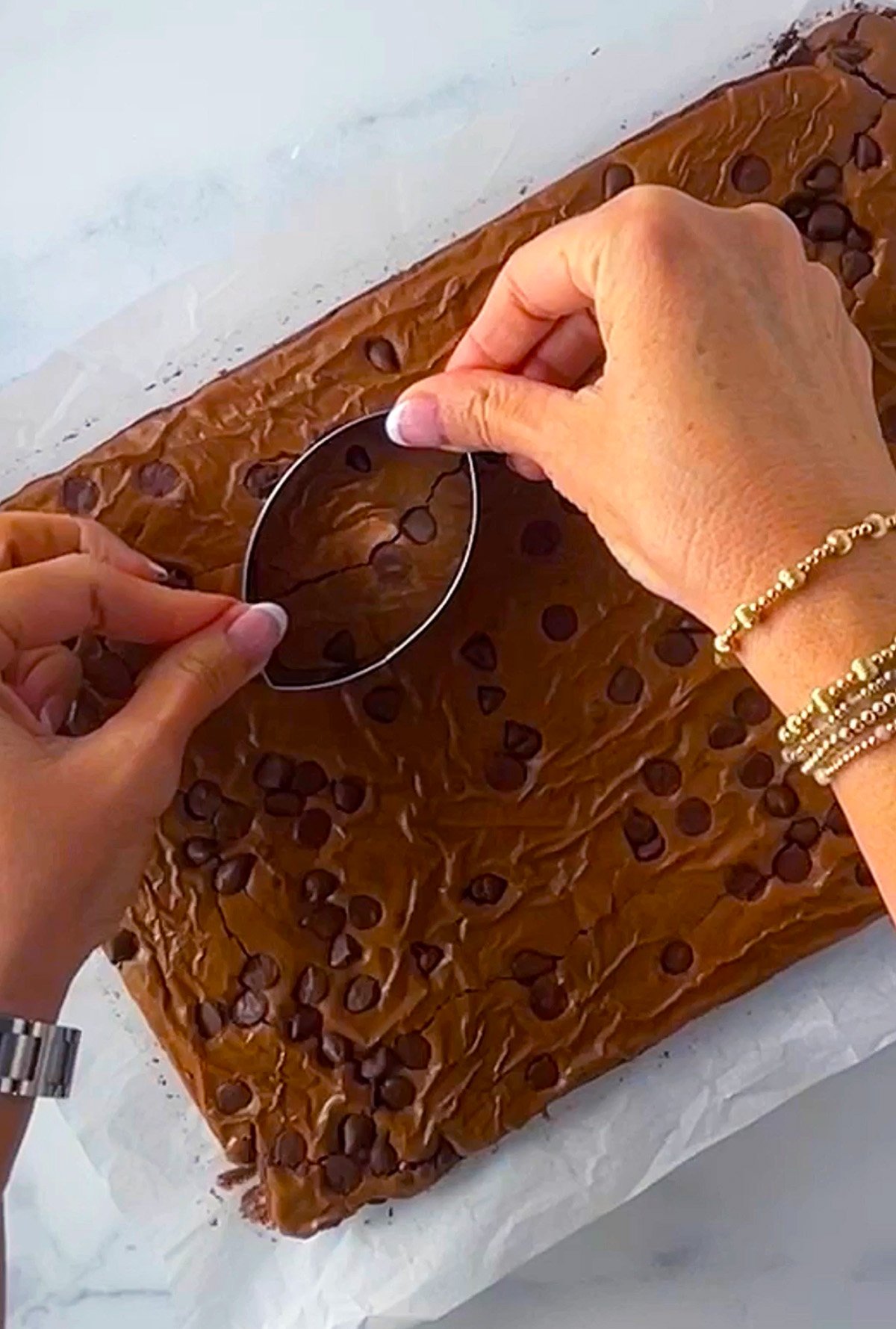 Cutting brownies with a football shaped cookie cutter.