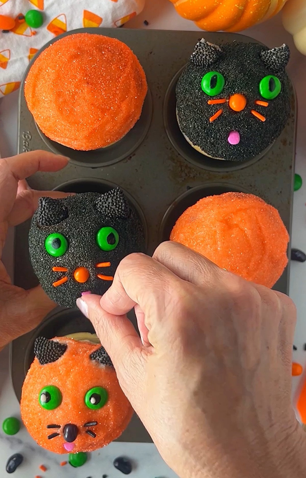 Decorating cat cupcakes with candies.