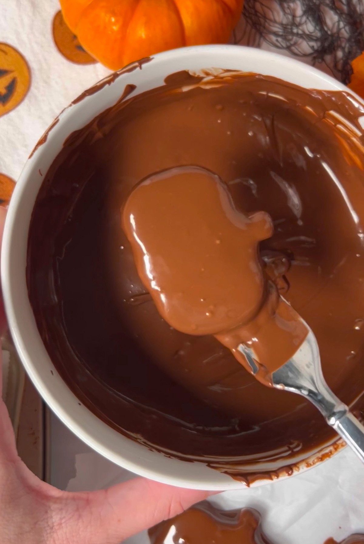 Dipping pumpkin shaped peanut butter cups in chocolate.