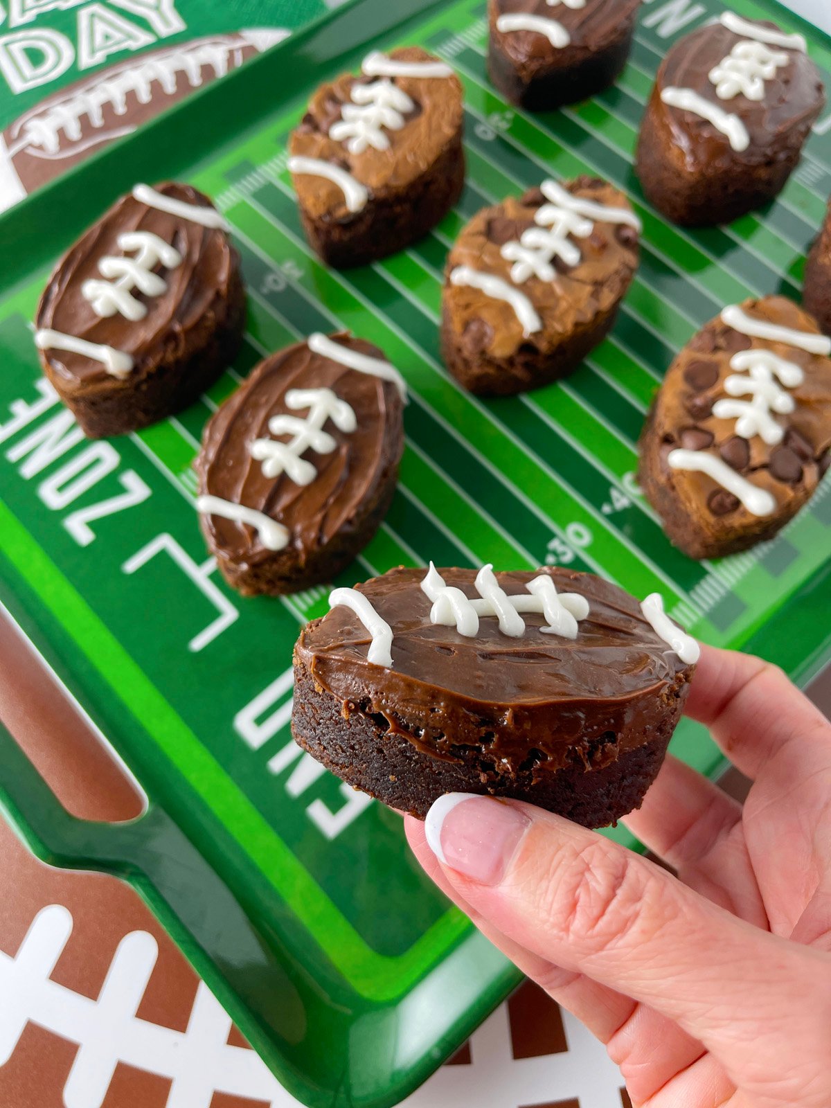 Hand holding a football shaped brownie.