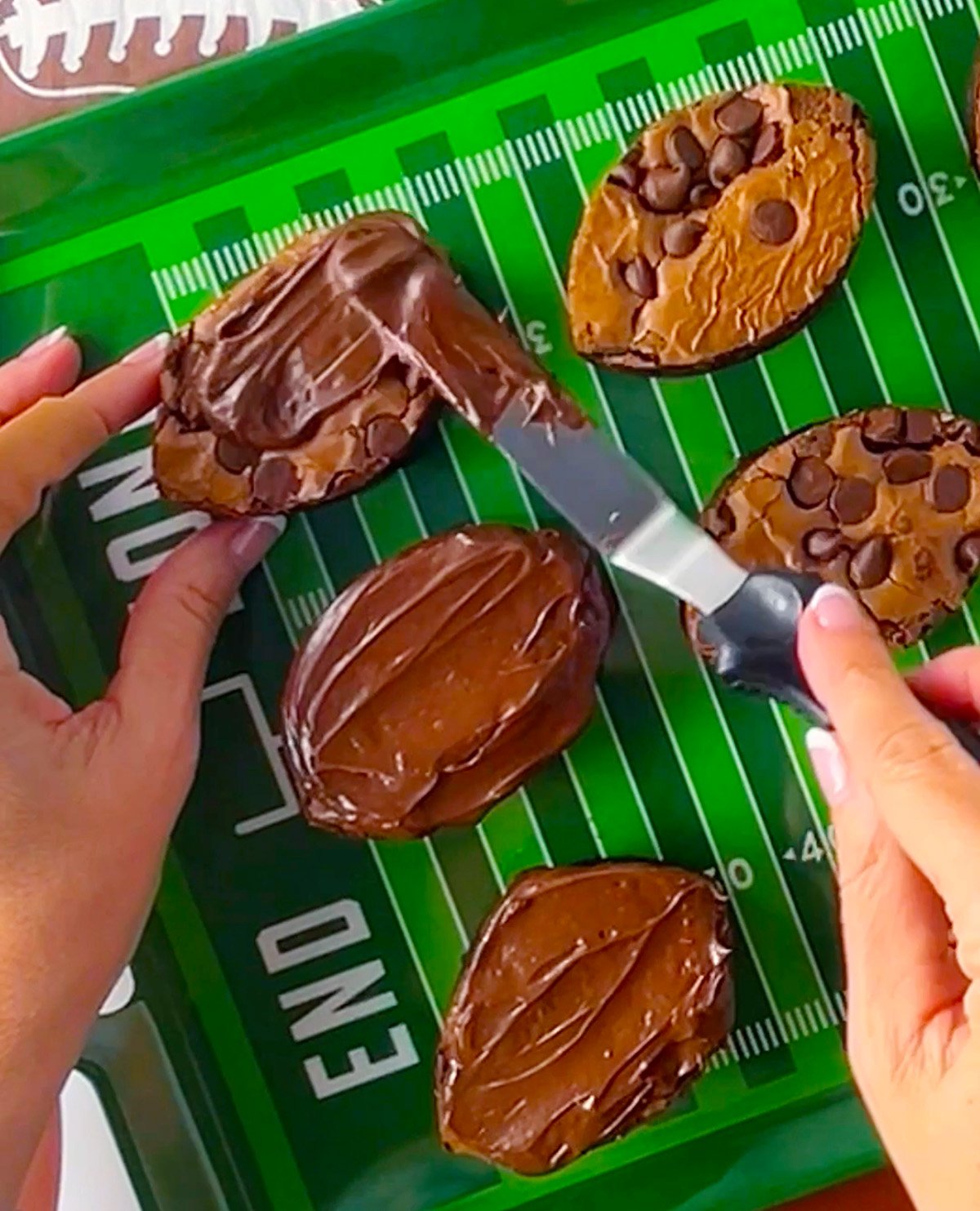 Frosting football brownies with canned chocolate fudge frosting.