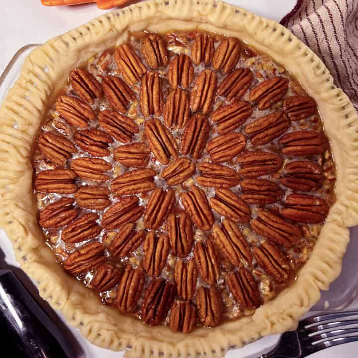 Pecan pie in homemade pie crust and pretty pecan design on top.