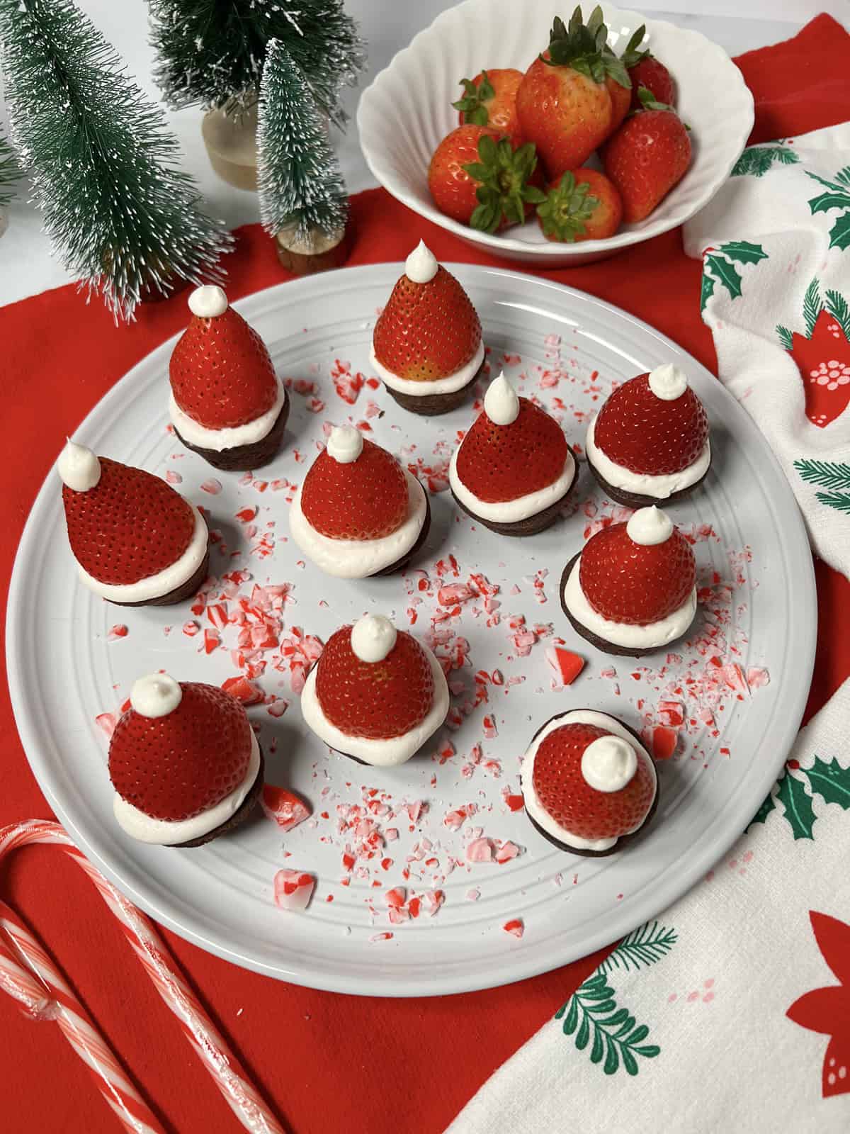 Lots of strawberry Santa hat brownies on a white plate.