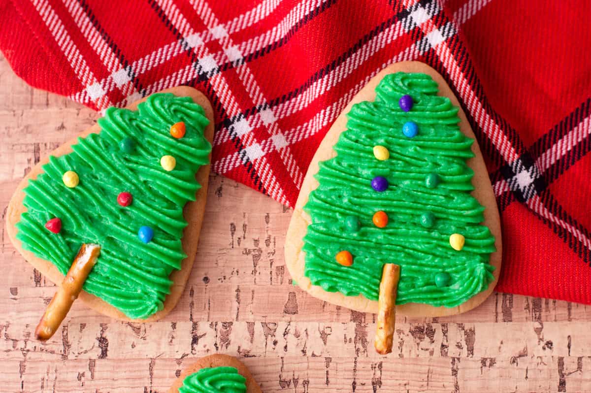 Cute Christmas Tree sugar cookies on a red plaid cloth towel.