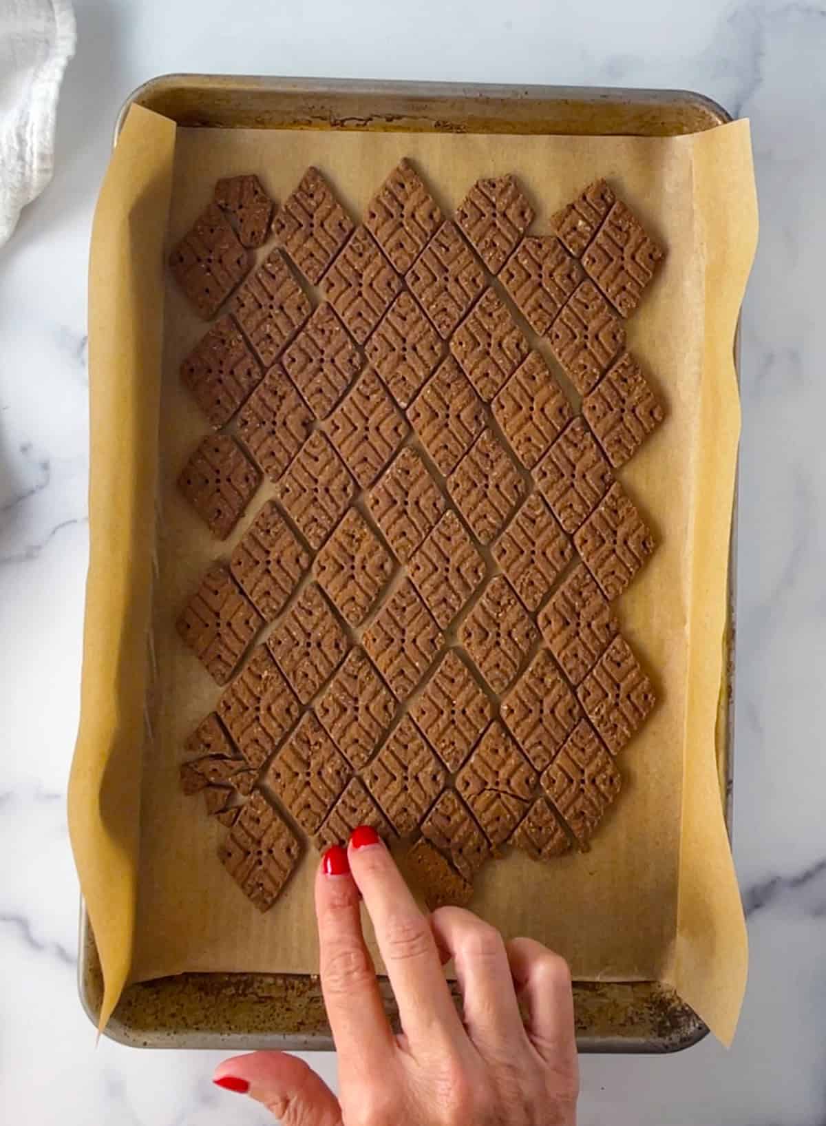 Chocolate graham crackers on a baking pan with parchment paper.