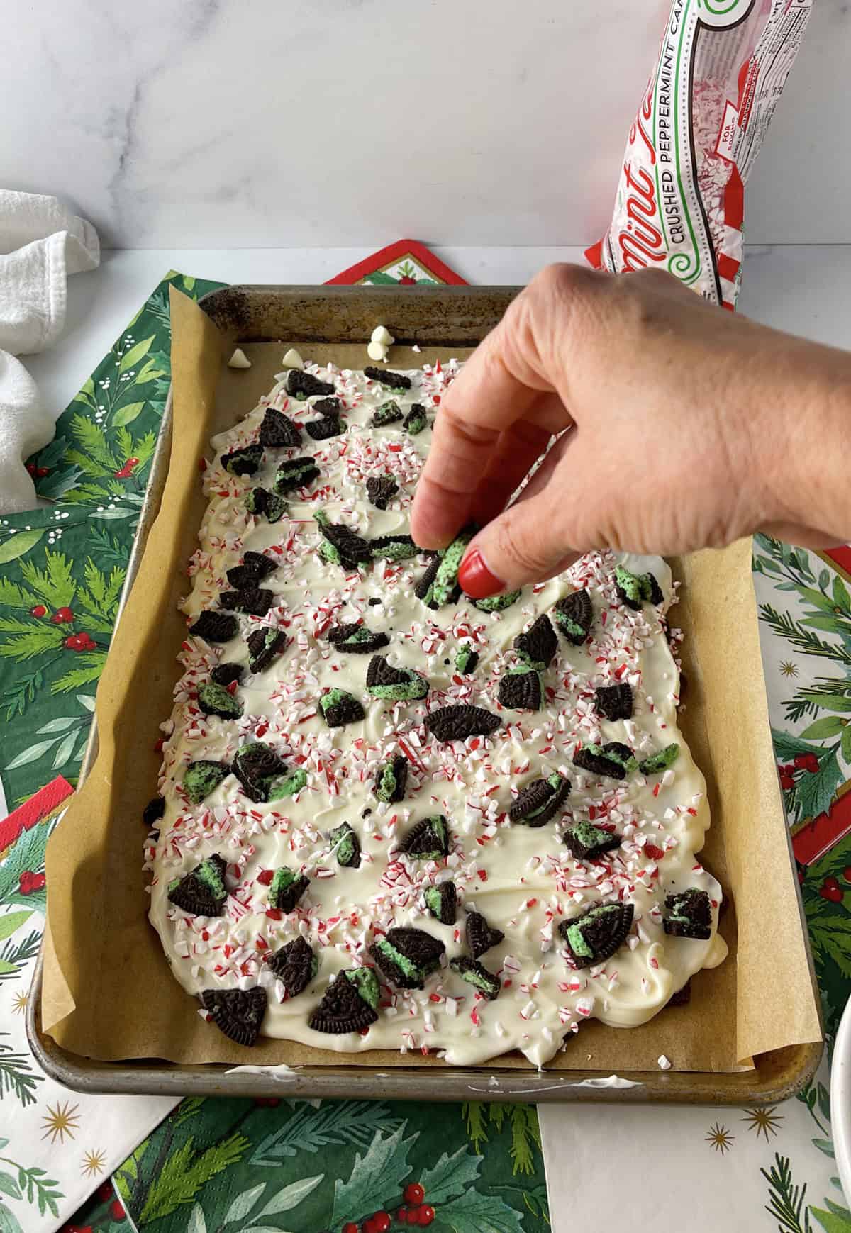 Sprinkling oreos on top of peppermint bark.