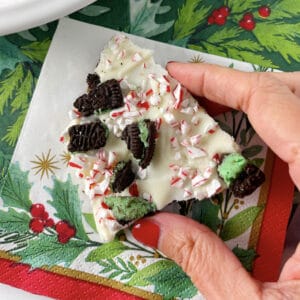 Hand holding piece of peppermint bark cracker toffee.